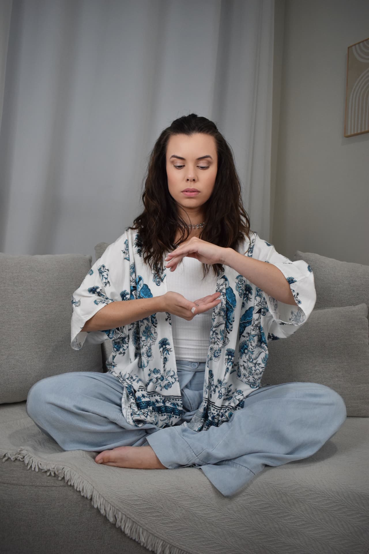 Debora sentada em casa, em posição de meditação, conduzindo uma prática de Reiki
